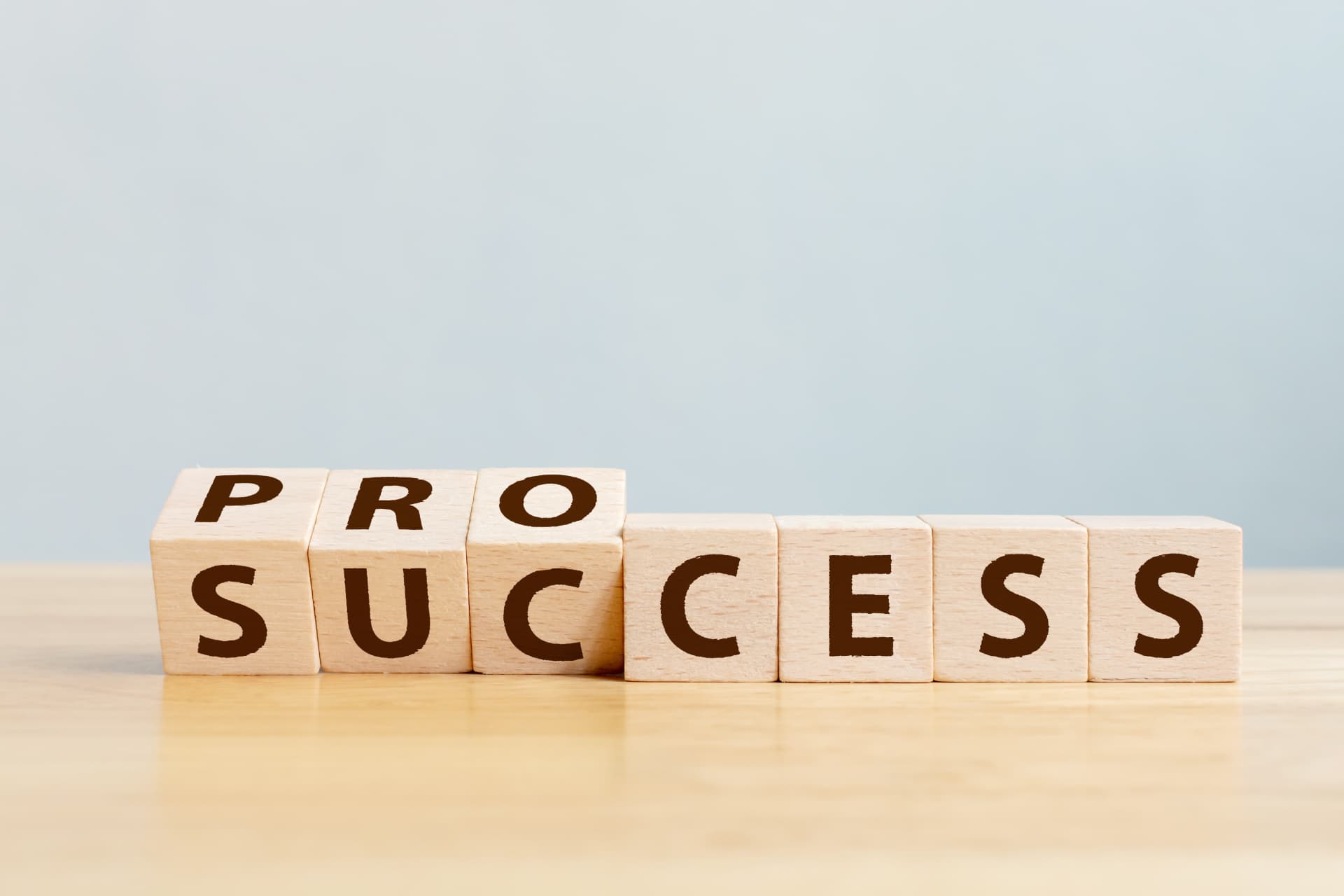 Wooden blocks connecting the words process and success